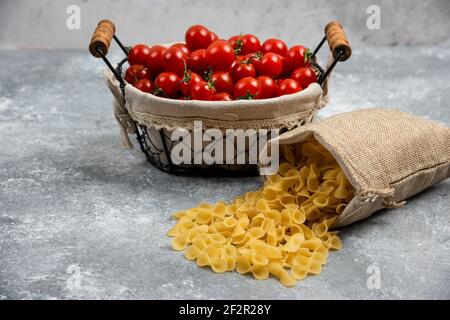 Rustikale Körbe von Pasta mit Kirschtomaten auf Marmor Hintergrund Stockfoto