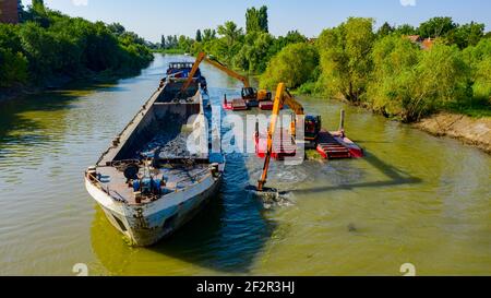 Oben auf zwei Bagger Bagger Baggern, wie sie Baggern, Arbeiten an Fluss, Kanal, Vertiefung und Entfernen von Sediment, Schlamm aus Flussbett in einem verschmutzten Wasser Stockfoto