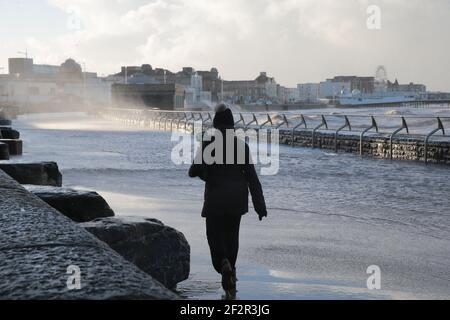 Weston Super Mare, Großbritannien, 13th. März 2021. Wetter in Großbritannien. Stürmische Winde im Weston Super Mare, während die Menschen entlang der Promenade kämpfen. Kredit: Gary Learmonth/Alamy Live Nachrichten Stockfoto