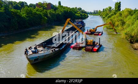 Oben auf zwei Bagger Bagger Baggern, wie sie Baggern, Arbeiten an Fluss, Kanal, Vertiefung und Entfernen von Sediment, Schlamm aus Flussbett in einem verschmutzten Wasser Stockfoto