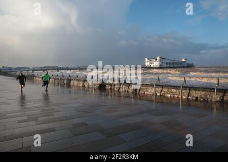 Weston Super Mare, Großbritannien, 13th. März 2021. Wetter in Großbritannien. Stürmische Winde im Weston Super Mare, während die Menschen entlang der Promenade kämpfen. Kredit: Gary Learmonth/Alamy Live Nachrichten Stockfoto