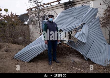 AGDAM, ASERBAIDSCHAN - DEZEMBER 14: Ein aserbaidschanischer Mann steht vor seinem Haus, das am 13. Oktober von einer Rakete, die von armenischen Streitkräften im Dorf Quzanli am 14 2020. Dezember im aserbaidschanischen Bezirk Jabrayil abgefeuert wurde, teilweise zerstört wurde. Ende September brachen schwere Zusammenstöße über Berg-Karabach aus, bei denen mehr als 5.600 Menschen, darunter Zivilisten, getötet wurden. Die Seiten einigten sich auf eine von Russland vermittelte Waffenstillstandsabkommen, die am 10. November in Kraft trat, was dazu führte, dass Aserbaidschan die Kontrolle über Teile des Territoriums wiedererlangt hatte, das ethnische Armenier seit fast 30 Jahren verwaltet hatten. Stockfoto