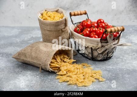 Rustikale Körbe von Pasta mit Kirschtomaten auf Marmor Hintergrund Stockfoto