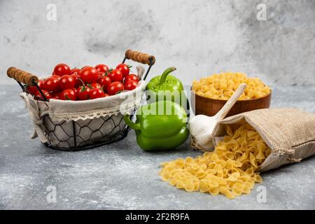 Rustikale Körbe mit Teigwaren mit Kirschtomaten, Pfeffer und Knoblauch Stockfoto