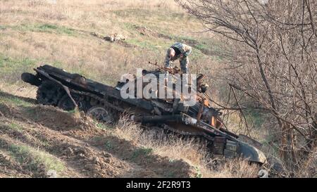 JABRAYIL, ASERBAIDSCHAN - DEZEMBER 15: Ein Mitglied der russischen Friedenstruppe untersucht einen zerstörten armenischen T-72-Panzer auf Überreste armenischer Kämpfer, die im Konflikt um die umstrittene Region Berg-Karabach am 15 2020. Dezember im Bezirk Jabrayil von Aserbaidschan getötet wurden. Ende September brachen schwere Zusammenstöße über Berg-Karabach aus, bei denen mehr als 5.600 Menschen, darunter auch Zivilisten, getötet wurden. Die Seiten einigten sich auf ein Waffenstillstandsabkommen, das am 10. November in Kraft trat Stockfoto