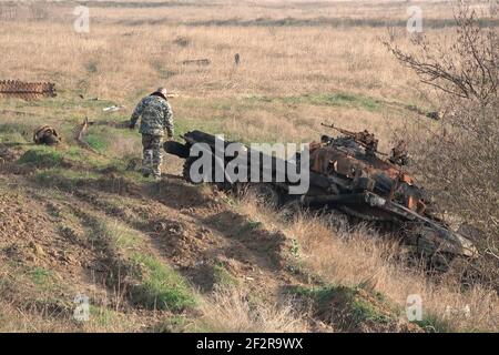 JABRAYIL, ASERBAIDSCHAN - DEZEMBER 15: Ein Mitglied der russischen Friedenstruppe untersucht einen zerstörten armenischen T-72-Panzer auf Überreste armenischer Kämpfer, die im Konflikt um die umstrittene Region Berg-Karabach am 15 2020. Dezember im Bezirk Jabrayil von Aserbaidschan getötet wurden. Ende September brachen schwere Zusammenstöße über Berg-Karabach aus, bei denen mehr als 5.600 Menschen, darunter auch Zivilisten, getötet wurden. Die Seiten einigten sich auf ein Waffenstillstandsabkommen, das am 10. November in Kraft trat Stockfoto