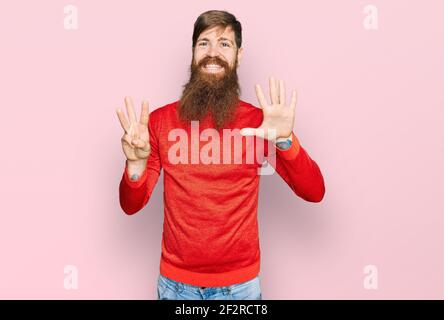 Rotschopf Mann mit langen Bart tragen lässige Kleidung zeigt und zeigt mit den Fingern Nummer acht, während lächelnd zuversichtlich und glücklich. Stockfoto