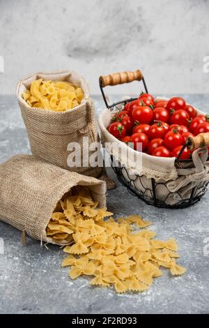 Rustikale Körbe von Pasta mit Kirschtomaten auf Marmor Hintergrund Stockfoto