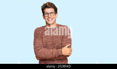 Schöner kaukasischer Mann trägt lässigen Pullover und Brille sieht positiv aus Und glücklich stehen und lächeln mit einem selbstbewussten Lächeln zeigen Zähne Stockfoto