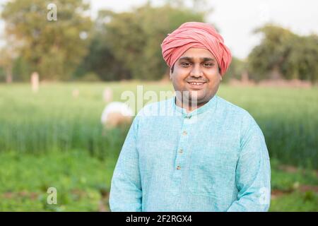 Portrait von jungen glücklichen indischen Landwirt tragen traditionelle Kurta Outfit stehen in der Landwirtschaft grünen Feld. Nahaufnahme beim Betragen der Kamera. Stockfoto