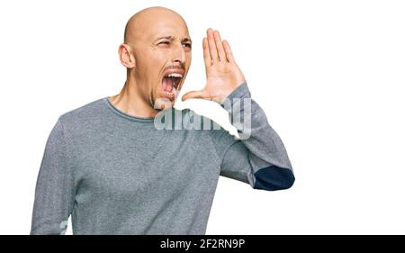 Glatze Mann mit Bart tragen lässige Kleidung schreien und schreien laut zur Seite mit Hand auf Mund. Kommunikationskonzept. Stockfoto