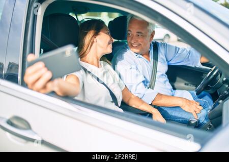 Mittelalterpaar verliebt sitzt im Auto gehen Für eine Reise, die ein Selfie-Bild mit Smartphone lächelt Glücklich und fröhlich zusammen Stockfoto