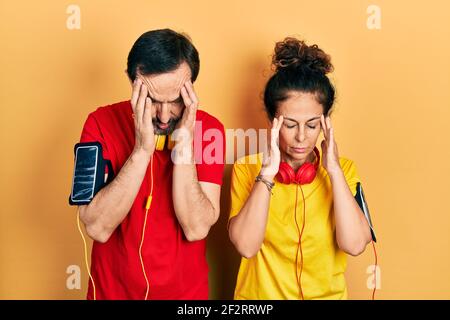 Mittelalterpaar hispanische Frau und Mann tragen Sportkleidung und Armband mit Hand am Kopf für Schmerzen im Kopf, weil Stress. Leiden Migräne. Stockfoto