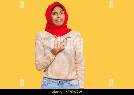 Junge afroamerikanische Frau trägt traditionelle islamische Hijab Schal zur Seite zeigt besorgt und nervös mit Zeigefinger, besorgt und überrascht expre Stockfoto