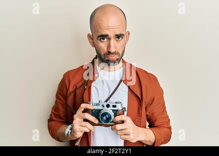 Junge hispanische Mann hält vintage Kamera deprimiert und sorgen für Not, Weinen wütend und Angst. Trauriger Ausdruck. Stockfoto