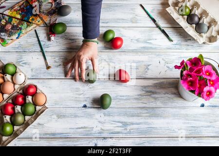 Frau hält Färbung Ostereier in ihren Händen. Tabellenansicht von oben. Herstellung handgemachte Osterdekoration Stockfoto