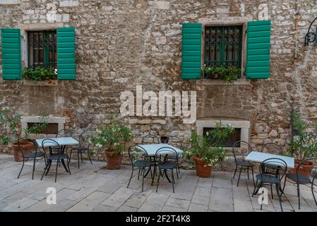 Restauranttische in einer engen Straße in der Altstadt von Sibenik, Kroatien Stockfoto