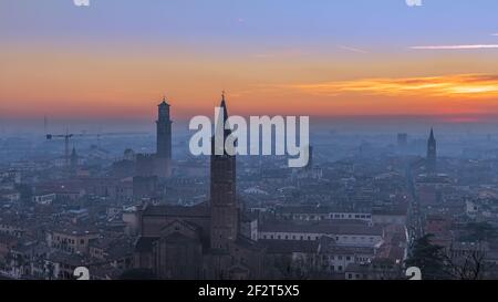 Schöne Panorama-Sonnenuntergang Blick auf die Altstadt von Verona, Torre Lamberti und Santa Anastasia Glockenturm mit Abendnebel bedeckt. Blick vom Piazzale Cast Stockfoto