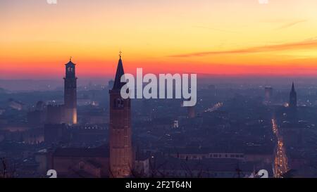 Schöne Panorama-Sonnenuntergang Blick auf die Altstadt von Verona, Torre Lamberti und Santa Anastasia Glockenturm mit Abendnebel bedeckt. Blick vom Piazzale Cast Stockfoto