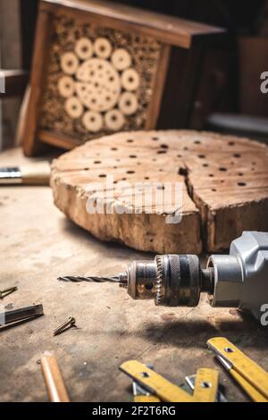 Herstellung von Holz Insekt Hotel oder Haus in der Werkstatt. Bohrer und Arbeitswerkzeuge auf dem Tisch. Schreinerei Ausrüstung Stockfoto