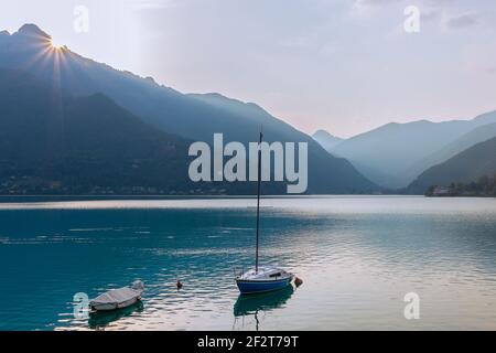 Eine minimalistische Landschaft des Idrosees mit einem Boot und Sonnig hinter den Felsen (Italien) Stockfoto