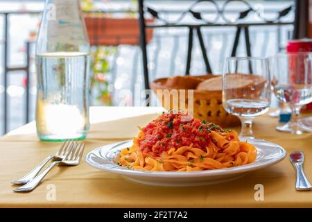Italienische Pasta (Fettuccine) mit Fischragu und Tomatensauce, im Hintergrund ein See. Ein typisches Gericht am Ufer des Piediluco Sees. Umbrien, I Stockfoto