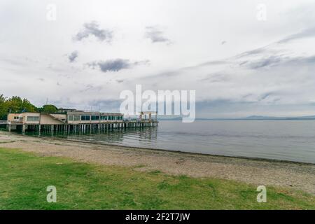 Schöne Aussicht auf den Trasimenischen See von einem einsamen Strand. Der Himmel ist bedeckt und ruhiges Wasser, keine Menschen. Nostalgische Stimmung. Umbrien, Italien Stockfoto