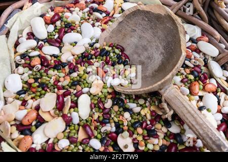 Zusammensetzung von verschiedenen Arten von Hülsenfrüchten. Kichererbsen, rote Linsen, gelbe Erbsen und verschiedene Arten von Bohnen in einem Holzkorb mit einem großen Holzmea Stockfoto