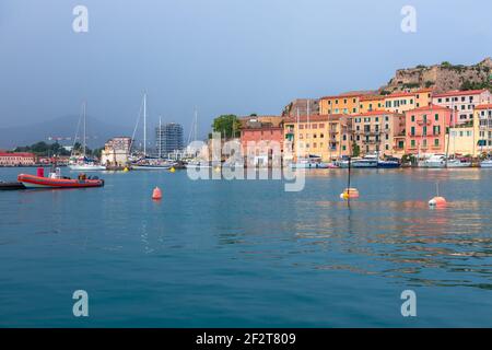 PORTOFERRAIO, INSEL ELBA, ITALIEN - 17. SEPTEMBER 2018: Schöne Aussicht auf den Hafen der Stadt Portoferraio. Leuchtend rotes Boot im Vordergrund und Colo Stockfoto