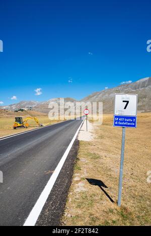 Leere Asphaltstraße über den malerischen Pian Grande in Castelluccio di Norcia, Umbrien, Italien. Straßenarbeiten entlang der Straße Stockfoto