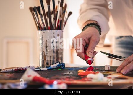 Künstler mischen Acrylfarben auf Palette für Malerei. Frau, die in ihrem Kunststudio arbeitet Stockfoto