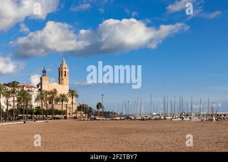 Schöne Aussicht auf die Kirche Sant Bartomeu und Santa Tecla in Sitges mit Booten am Strand unter dem schönen Himmel. Stockfoto