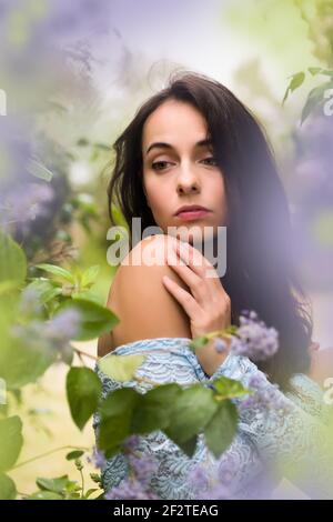 Schöne junge Frau in einem Sommergarten mit lavendelfarbenen Blumen Stockfoto