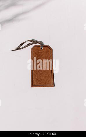Braunes Etikett mit Glas auf einem weißen Tisch mit Schattierungen, fügen Sie einen Text auf einem Tag oder Ihr eigenes Design-Element hinzu Stockfoto