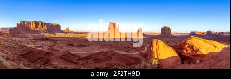 Spätes Sonnenlicht erhellt die Mitten und Merrick Buttes, Mesas und gewundene Pfade in einem weiten Panorama des Monument Valley, USA. Stockfoto