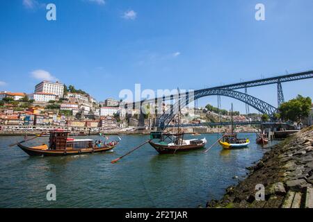 Schiffe auf dem Fluss Douro in Porto, mit der ikonischen Dom Luis Brücke im Hintergrund. Stockfoto