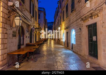 Sonnenaufgang Blick auf die Restauranttische in einer engen Straße in der Altstadt von Dubrovnik, Kroatien Stockfoto