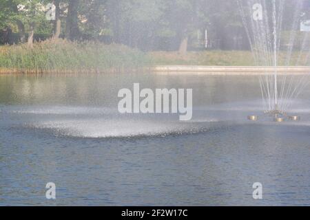 Spritzer und Tropfen auf dem Wasser des Sees vom Brunnen. Nebelansicht, selektiver Fokus. Stockfoto