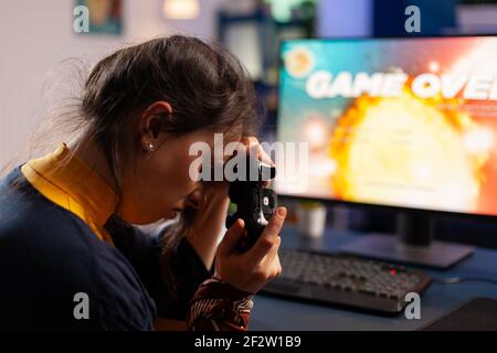Professionelle Gamer halten ihren Controller auf der Hand nach dem Verlust Weltraum-Shooter-Spiel mit drahtlosen Joystick. Konkurrenzfähiger Spieler mit moderner Ausrüstung für Online-Meisterschaft Stockfoto