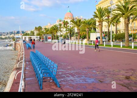 Leere blaue Stühle auf einer ruhigen Promenade des Anglais im Herbst. Nizza, Südfrankreich. Stockfoto