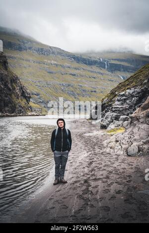 Junger Tourist, der im saksun-Tal auf einem Wanderweg auf den färöer-Inseln auf der Hauptinsel Streymoy steht. Stockfoto