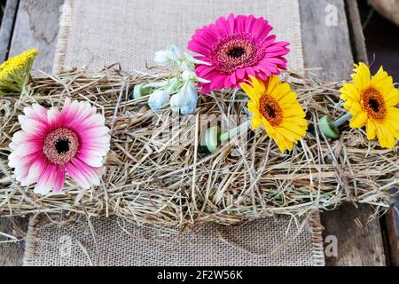 Tischdekoration mit Heu und Gerbera Blumen. Partydekor Stockfoto