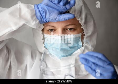 Müde Arzt in PSA Anzug aus COVID-19, Porträt von erschöpften Frau Arzt in professioneller Schutzkleidung wegen Coronavirus Pandemie, weiblich n Stockfoto