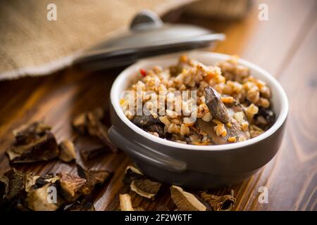 Gekochter Buchweizen mit Bio-Waldpilzen in einer Keramik Schüssel auf einem Holztisch Stockfoto