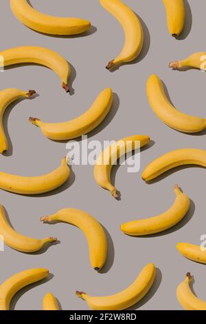 Kreatives Muster mit gelben Bananen auf grauem Hintergrund. Minimales ästhetisches Konzept. Stockfoto