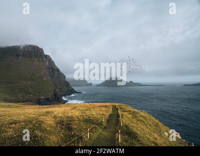 Färöer-Inseln mit stürmischer Sicht auf Tindholmur und Drangarnir auf der Insel Vagar vom Mulafossur-Wasserfall aus gesehen. Niedrige Wolken mit atlantik Stockfoto