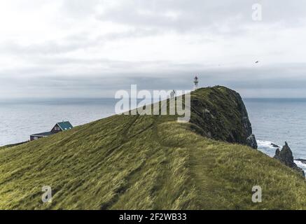Blick zum Leuchtturm auf der Insel Mykines Holmur, Färöer Insel ein bewölktes Tag mit Blick auf den Atlantik. Stockfoto