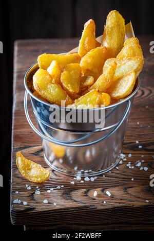 Goldene Chips mit Salz in einem kleinen Metalleimer. Amerikanische Küche. Stockfoto