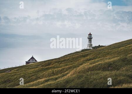 Blick zum Leuchtturm auf der Insel Mykines Holmur, Färöer Insel ein bewölktes Tag mit Blick auf den Atlantik. Stockfoto