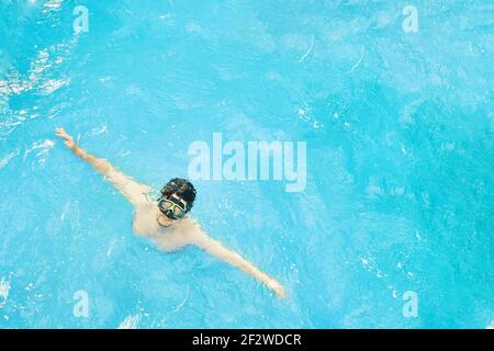 Der Mensch in einer Unterwassermaske taucht aus dem Wasser auf. Tauchen im Meer im Urlaub. Der Kerl mit ausgestreckten Armen. Sommerruhe. Stockfoto